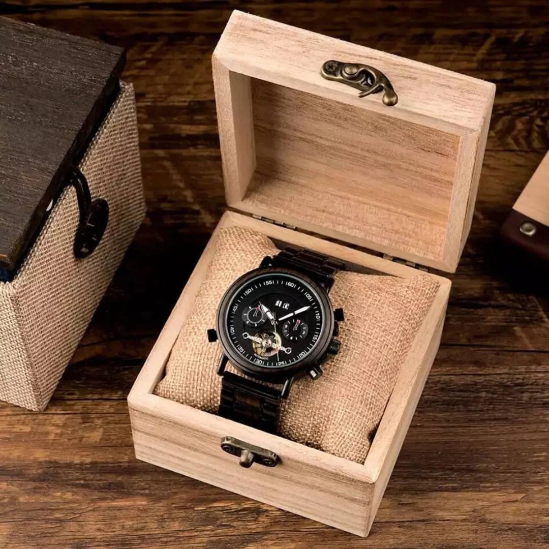 Black analog wristwatch in a wooden gift box on a rustic wooden table
