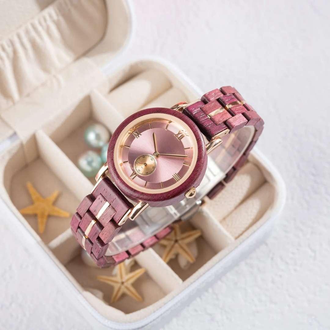 Rose gold and wood women's wristwatch displayed on jewelry box with starfish and pearls