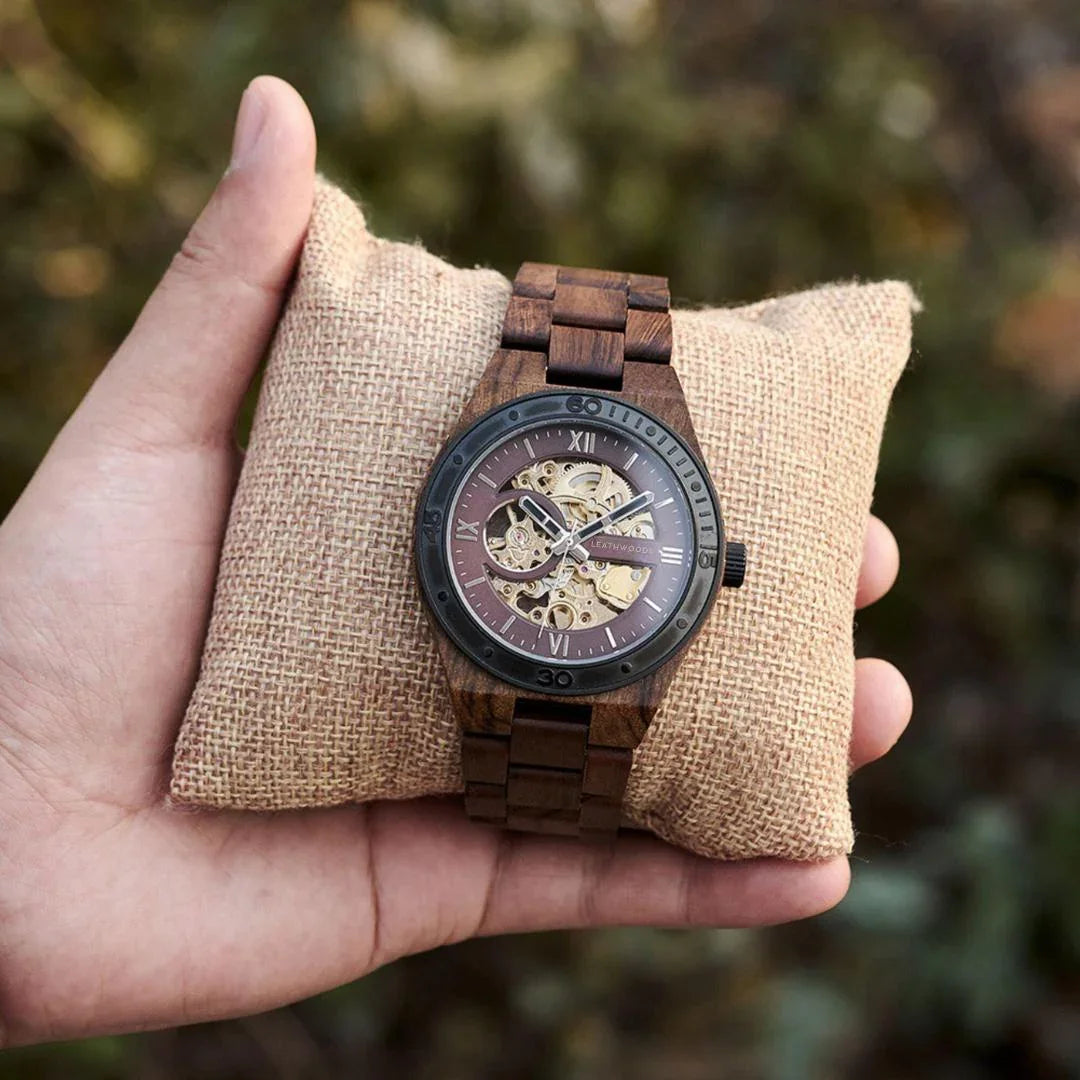 Hand holding a wooden skeleton watch on a burlap pillow outdoors
