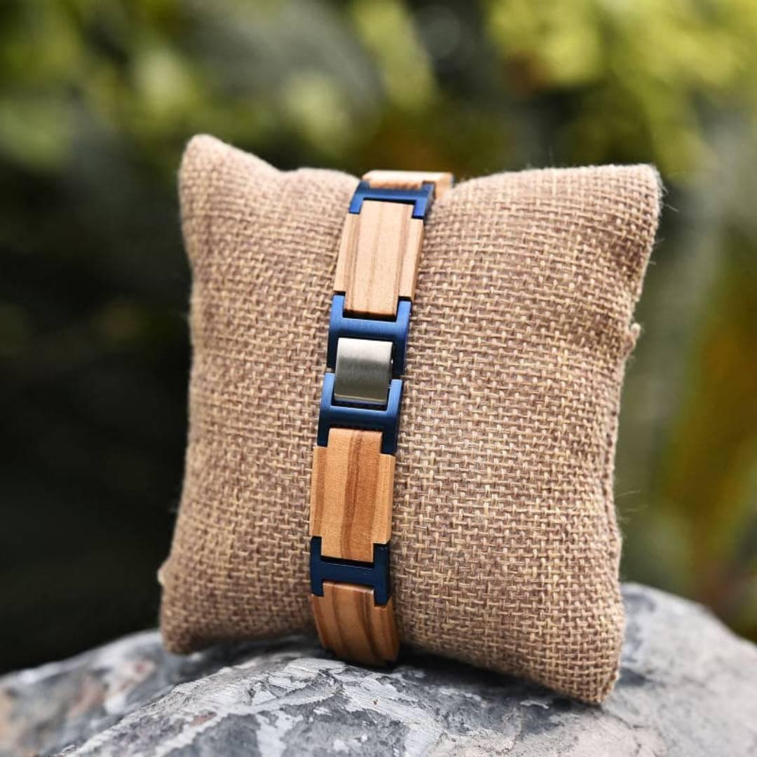 Men's wood and metal link bracelet on burlap pillow, displayed outdoors on a rock