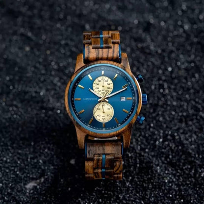 Wooden wristwatch with blue dial, gold markers, chronograph, and date on textured black surface