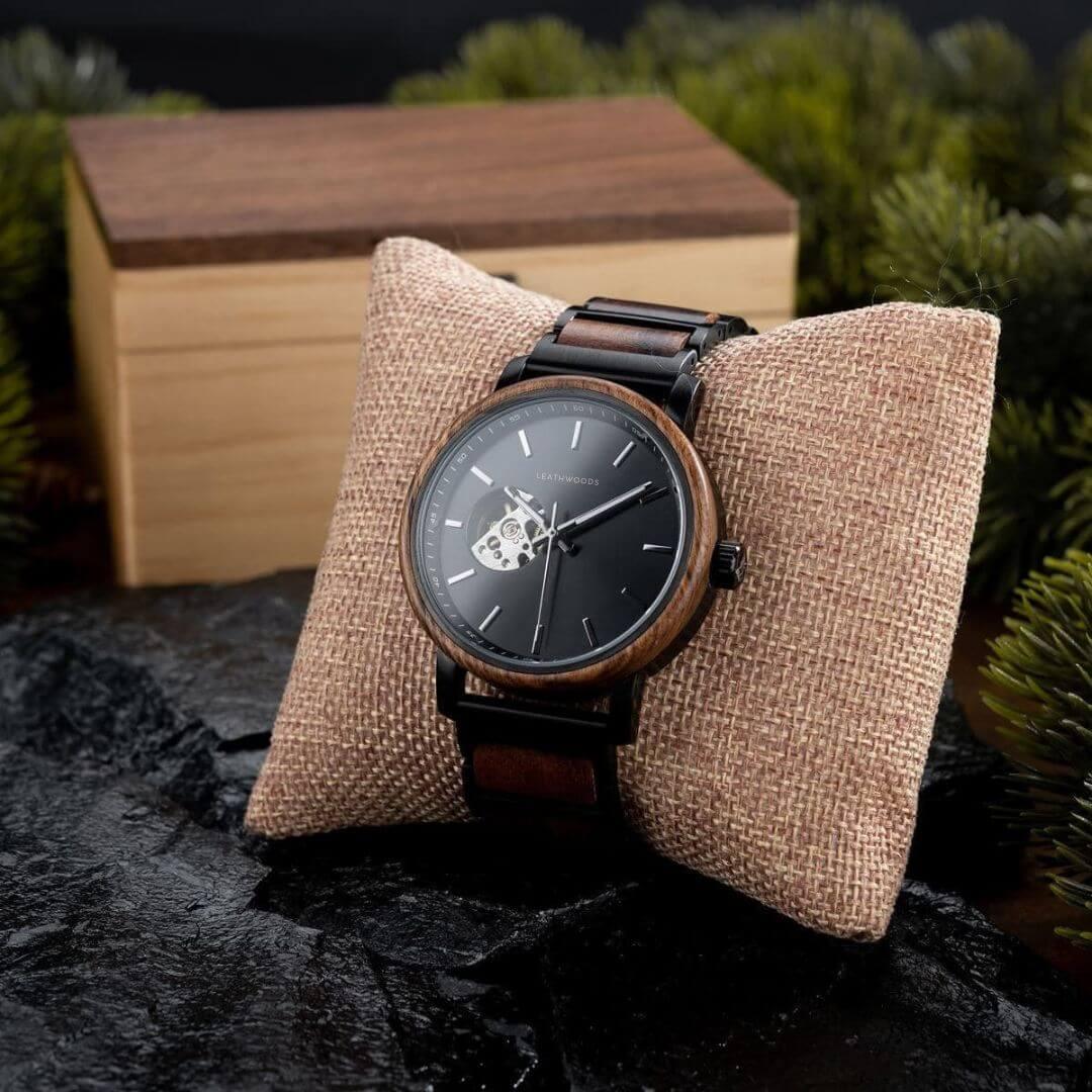 Leathwoods wooden wristwatch with black dial on textured cushion and wooden box backdrop