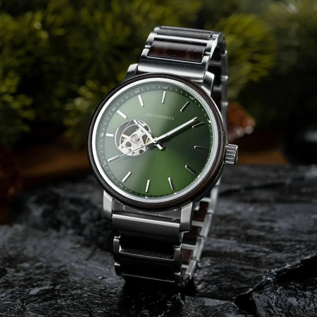 Leathwoods wristwatch with green dial, silver metal band, and visible watch mechanism on black stone surface