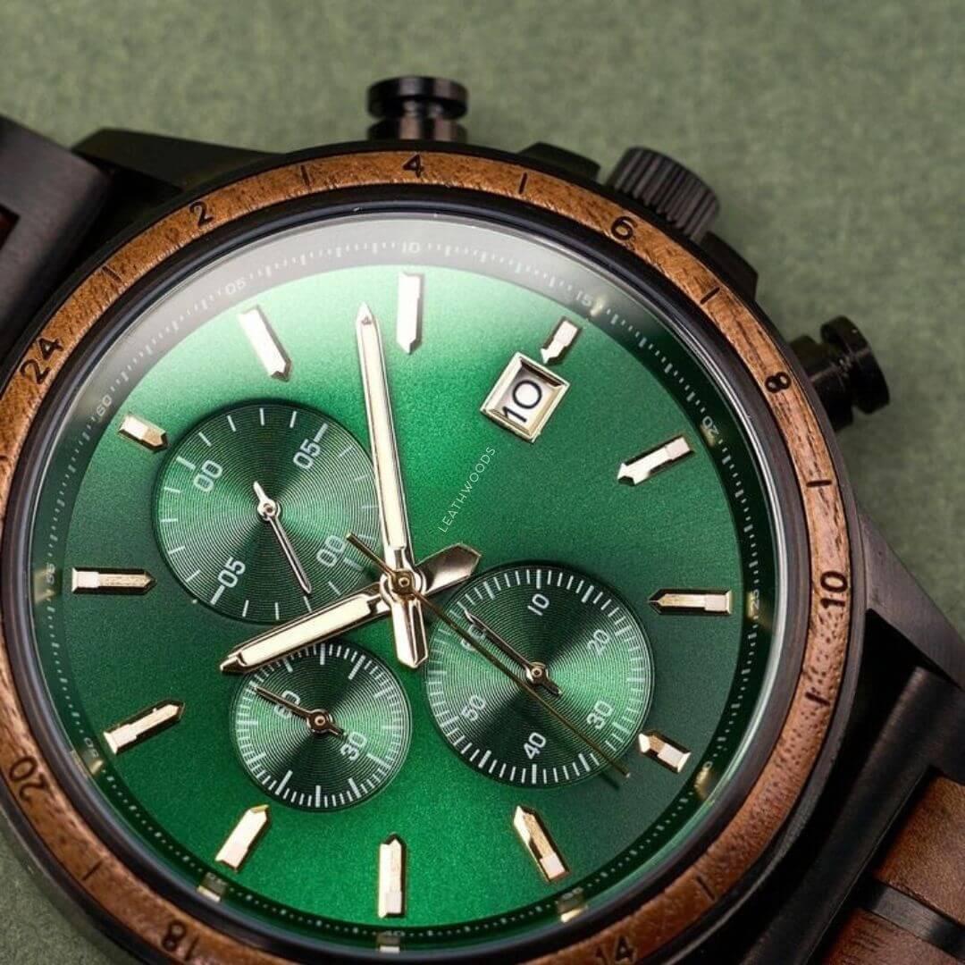 Close-up of a wristwatch with a green dial, wooden bezel, three subdials, and date display