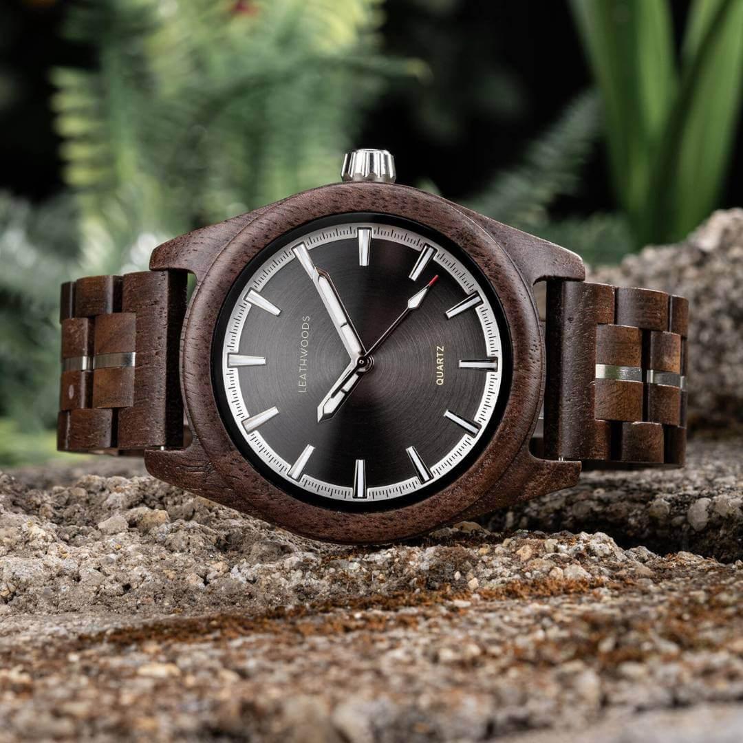 Close-up of a Leathwoods wooden wristwatch with black dial and silver markers on textured stone surface