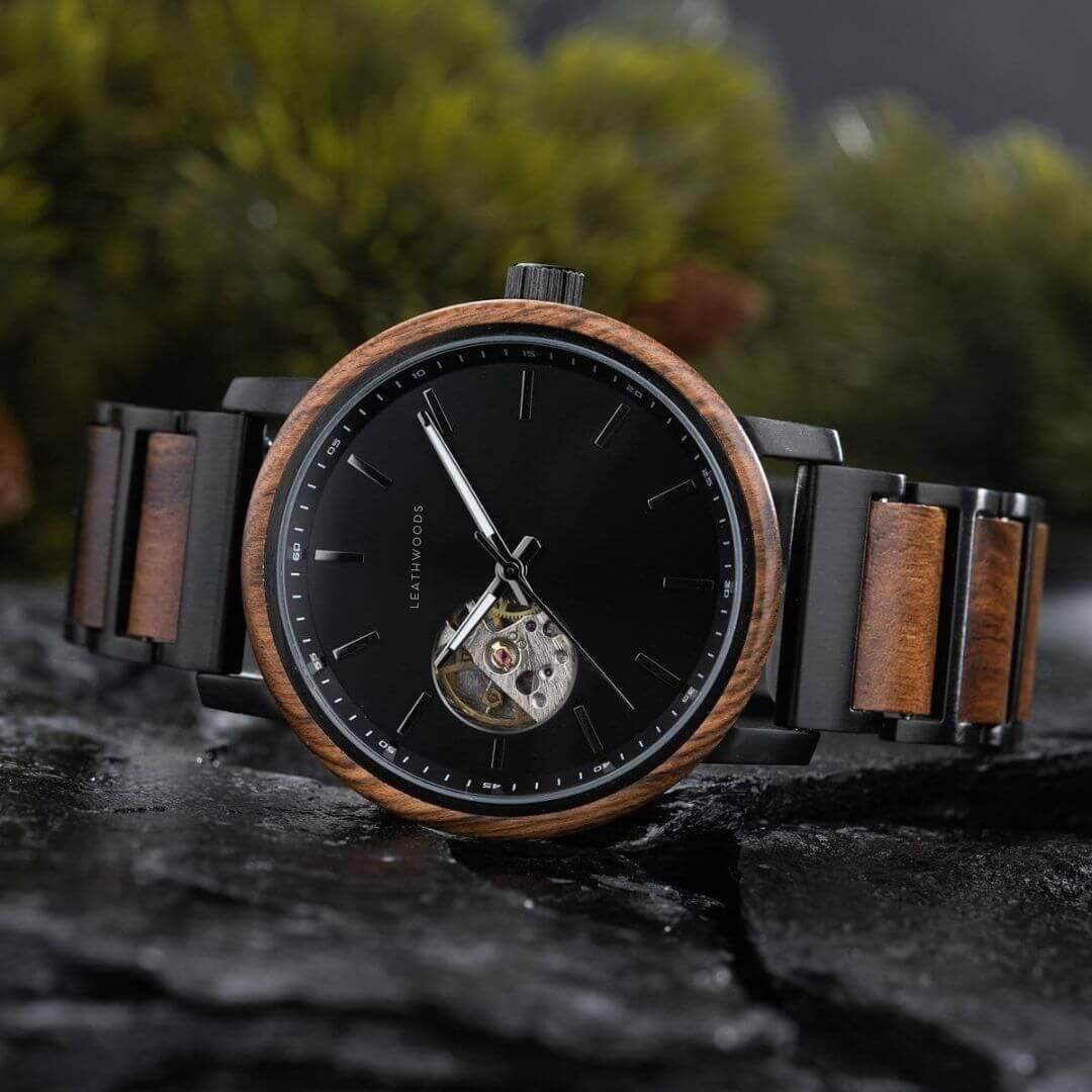 Leathwoods men's wristwatch with black dial, wooden bezel, and black wooden band on stone surface