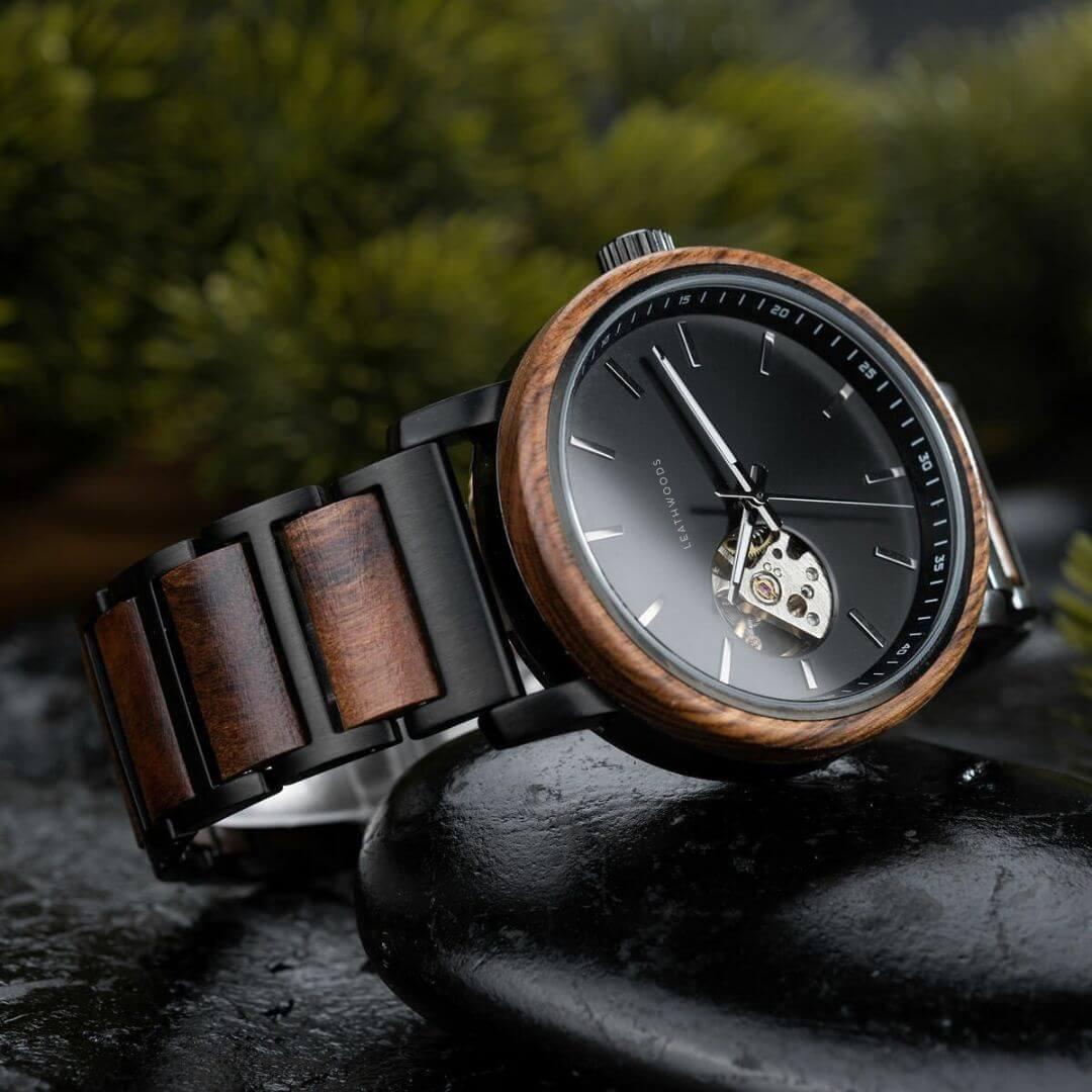 Luxury wristwatch with wooden bezel and black dial, featuring visible mechanical movement and wooden links