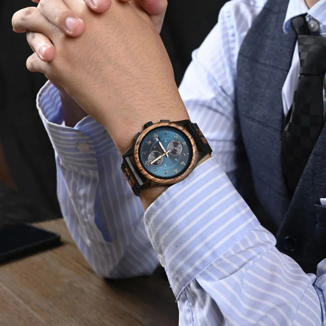 Man in striped shirt wearing a blue dial wooden wristwatch at a desk