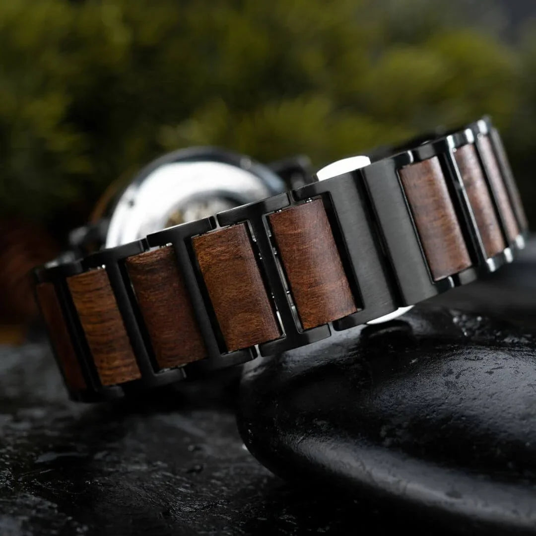 Close-up of metal and wood link watch band with blurred background on dark surface