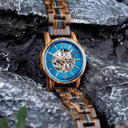 Wooden watch with blue face on a rocky surface