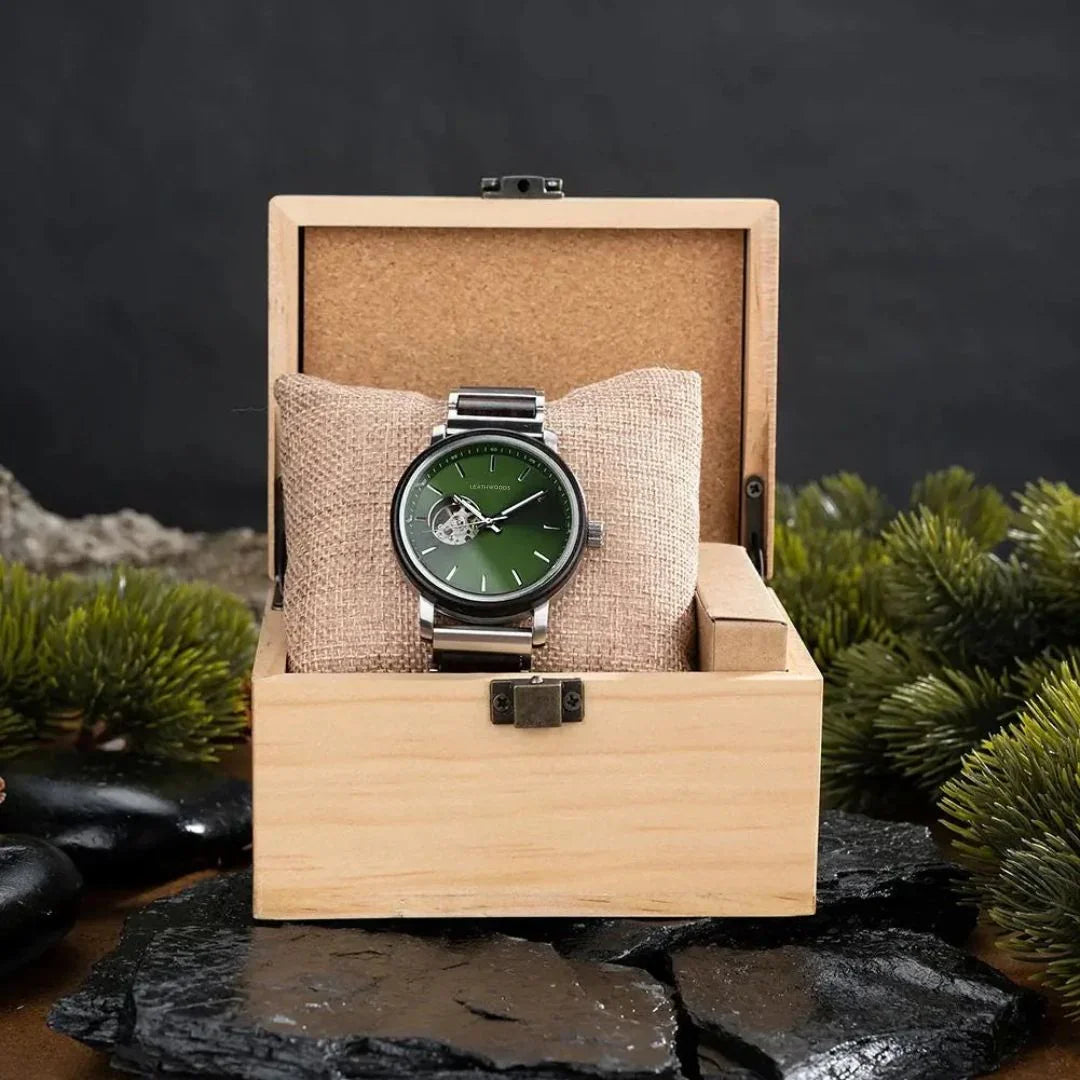 Men's luxury wristwatch with green dial in wooden box on stone and plant background